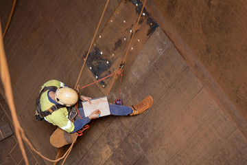 Miner rope access engineer planer  working at height abseiling into the chute,  writing, drawing...
