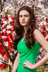 Young girl posing near blossom cherry tree with white flowers