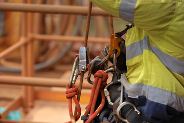 Rope access industry abseiler worker working at height abseiling removing rope from chest harness...