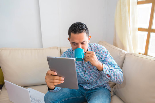 A man reading a message about an online contest on a digital tablet while drinking coffee
