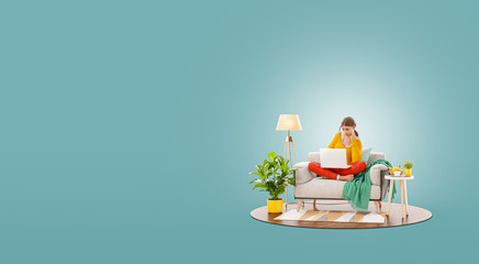 Young pretty female working on laptop computer sitting on a couch at her home office.