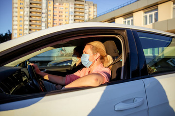 A family with children rides in their car in medical masks, self-isolation in the car, quarantine