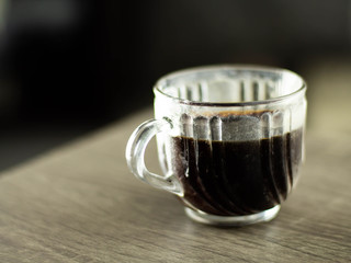 Transparent coffee mug Resting on a gray wooden table blurred background.