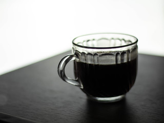 Transparent coffee mug Resting on a gray wooden table White light background.