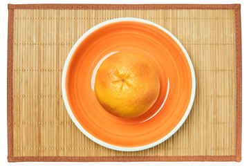 rosy yellow grapefruit on an orange plate on a cane tablecloth
