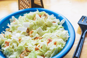 Green leaves of Beijing cabbage and pieces of fried chicken in a bowl. Cooking Caesar Salad.
