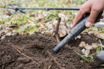 pinpointer metal detector in digger hand and ancient coin. Search for precious old historical coins...