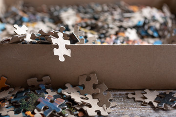 A closeup view of a puzzle piece hanging off the edge of the cardboard box.