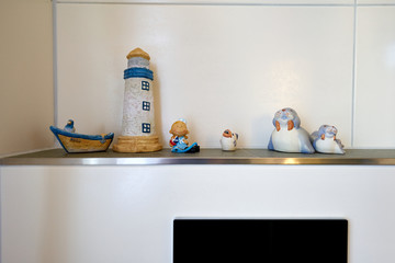 Black and white tiles in the bathroom, various colored figures made of clay on a shelf, the operating plate can be seen, Germany.