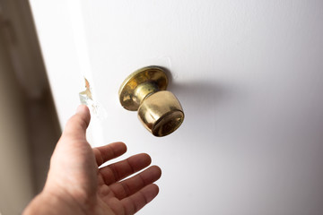 A view of a hand preparing to grab a door knob.