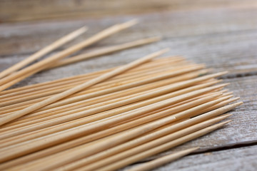 A closeup view of a pile of bamboo skewers on a wooden surface.