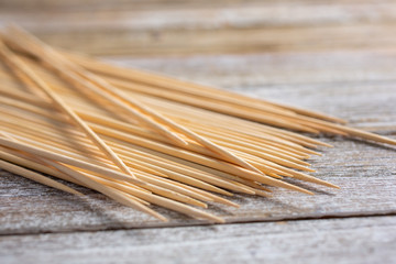 A closeup view of a pile of bamboo skewers on a wooden surface.