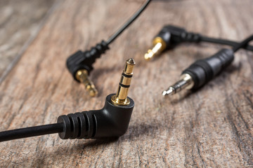 A closeup view of several 1/8 inch audio cable connectors, on a wooden surface.