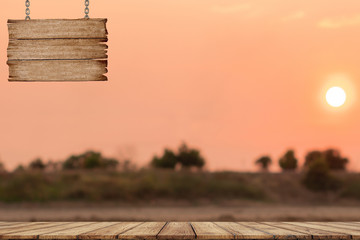 Wooden board and wooden sign hanging with a chain on sunset background
