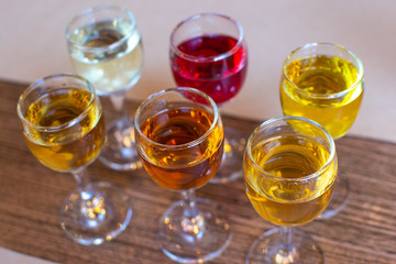 Colourful set of alcoholic cocktails in shot glasses shooters on wooden table for an alcoholic party. Set of traditional liquors and tinctures.