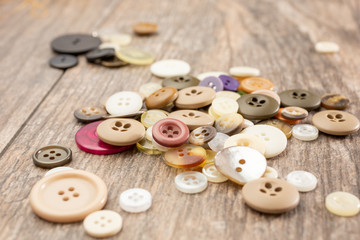 A closeup view of a small pile of clothing buttons, on a wooden surface.