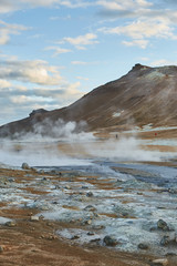 Unearthly view of soaring geysers and hot springs in famous valley located in Iceland. Mountain on the background. Geothermal area