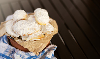 Homemade shortbread cookies with powdered sugar on the wood table in a clay plate with blue and white towel around. free space for text