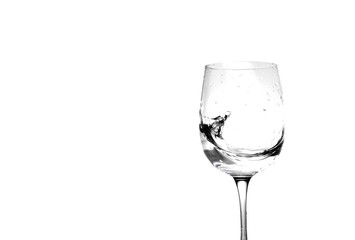 Water in a wine glass. Splash of liquid on a white background. Isolated object. Spray. Copy space for text. Selective focus.