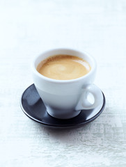 Cup of coffee on bright wooden background.