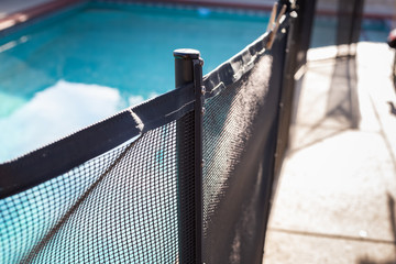 A closeup view of a swimming pool fence post, in a home backyard setting.