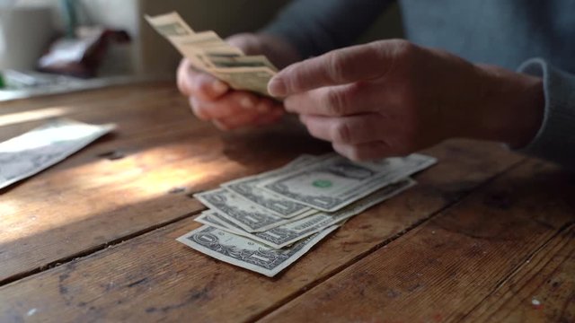 Elderly poor woman pensioner counts dollar bills of small denomination