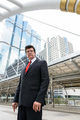 Mature handsome businessman in front of modern building at Bangkok city