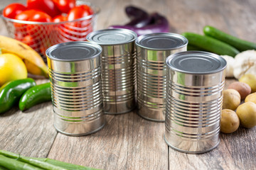A view of several metal food cans that have no label, in a still life setting.