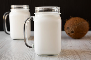 Coconut milk in glass jars, side view. Close-up.