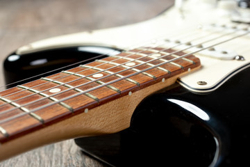 A closeup view of the neck and body of a black and white electric guitar.