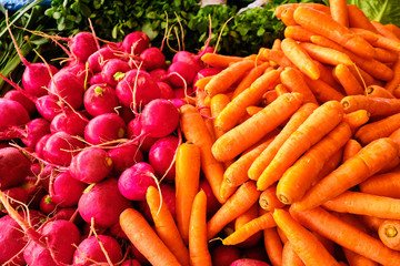 pink radish and orange carrots at market counter