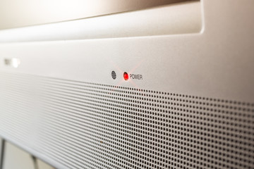 A closeup view of a television set with a red illuminated light that remains on when the device is off.