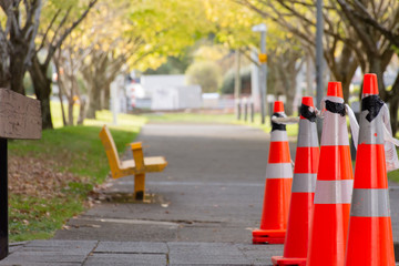 Orange and a yellow seat cones on a concrete path between trees