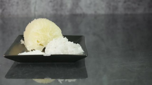 Slider shot on "ubi rebus" or steam cassava with sugar and grated coconut insight.