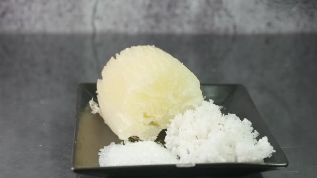 Slider shot on "ubi rebus" or steam cassava with sugar and grated coconut insight.