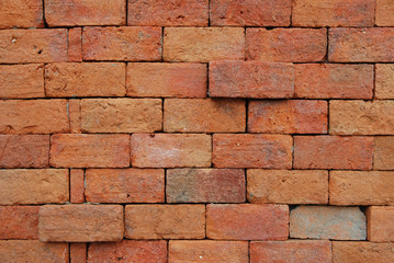 Close up of orange brick wall with uneven surface at some bricks