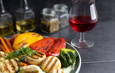 Fresh organic grilled vegetables bell pepper,mushrooms,broccoli,cauliflower,carrots seasoned with herbs on a round plate.