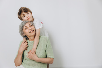 A little boy and his grandmother are having fun together against a light background