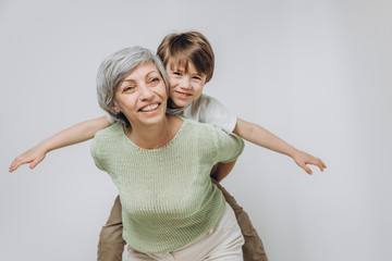 A little boy and his grandmother are having fun together against a light background