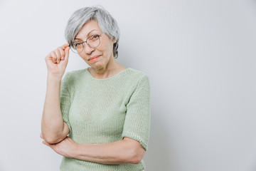 Elderly woman posing in a studio against a light background with copy space