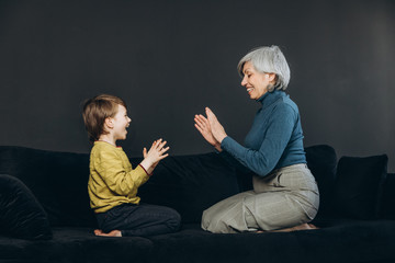 A little boy and his grandmother are having fun together against a dark background