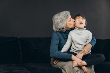 A little boy and his grandmother are having fun together against a dark background