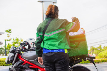 The female staff prepares food in the bag on the motorcycle to deliver the food to the customers ordered online.