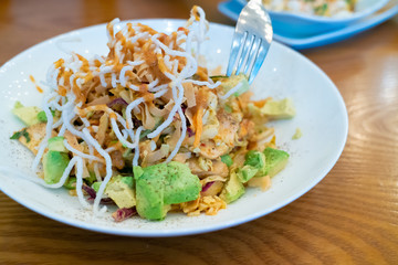 Avocado salad with crunchy noodles on top and fork.
