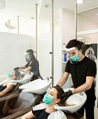 Servizio di lavaggio capelli dentro un salone da parrucchieri con tutte le disposizioni di protezione quali mascherine facciali,  - obrazy, fototapety, plakaty