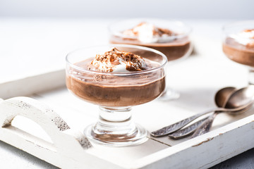 Vegan avocado, banana and cocoa mousse. Topped with coconut whipped cream and dark chocolate. White background