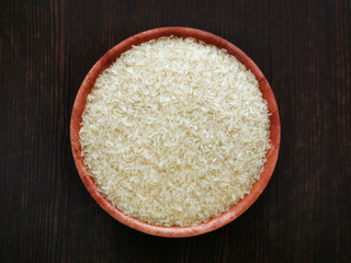 Parboiled rice on bamboo bowl on wood table.  Selective focus.  Top view.