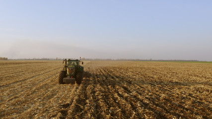 Fototapeta premium Green tractor working on field. Tractor plow field. Modern agrictulture machinery.