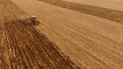 Tractor working on the field, top view. Endless agricultural field after harvesting. Farm works concept.