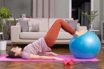 Young sporty woman using an exercise ball in her house.